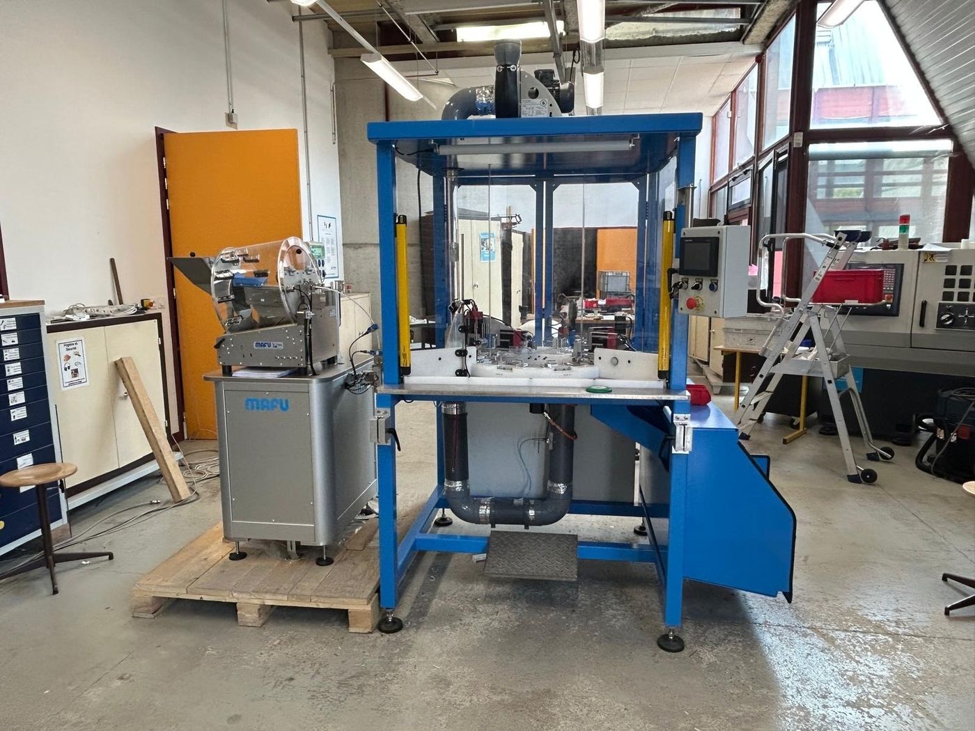 Assembleuse vue de face : bol d'alimentation, plateau tournant, barrières immatérielles et pupitre opérateur.