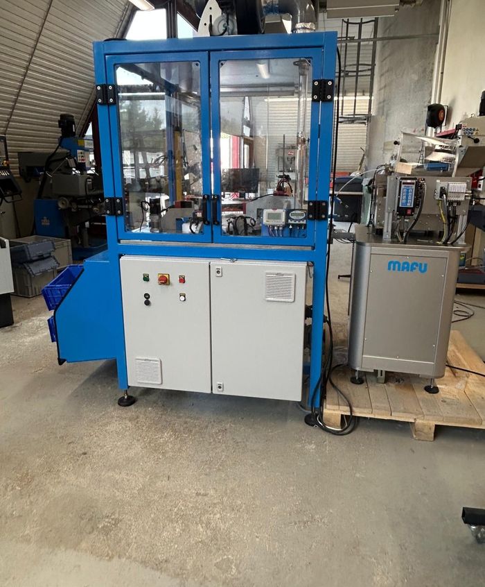 La même machine vue de côté, avec son armoire électrique et le bol d'alimentation.